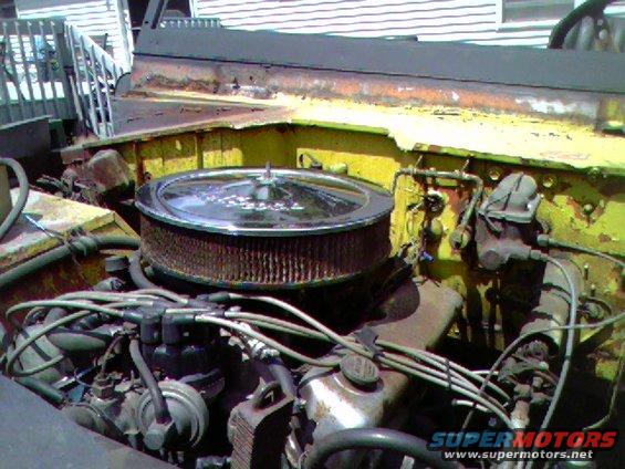 Yellow 1974 Ford Bronco engine bay with chrome air cleaner and visible engine components