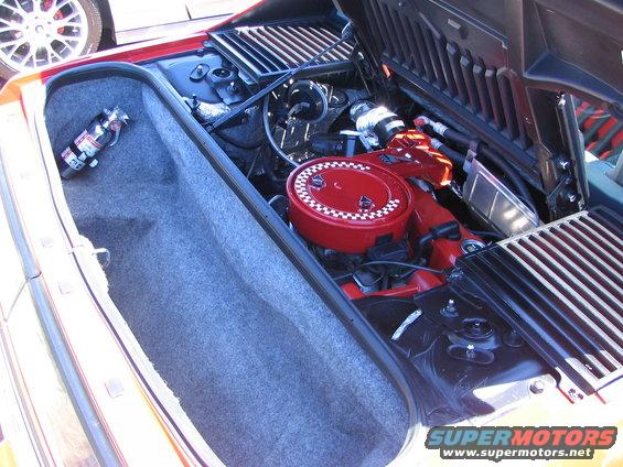 1986 Pontiac Fiero engine bay with red air cleaner and fire extinguisher in trunk