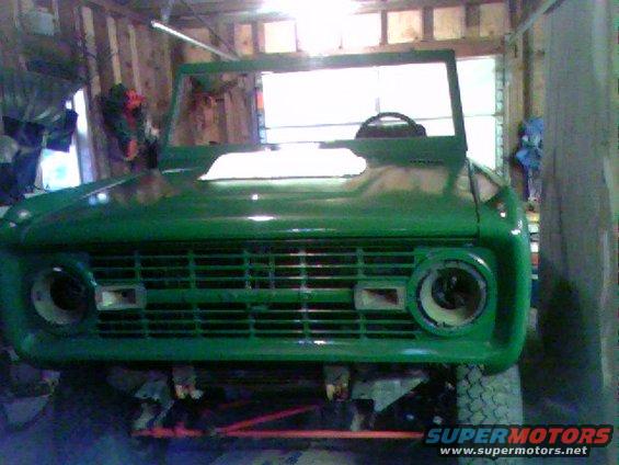 Green 1974 Ford Bronco front end in garage, missing headlights