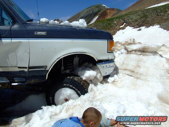 Ford Bronco stuck in snow on a mountain road, someone is digging it out