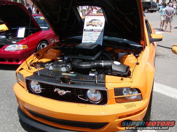 Orange Mustang with hood open showing engine. Sign says 2007 Saleen