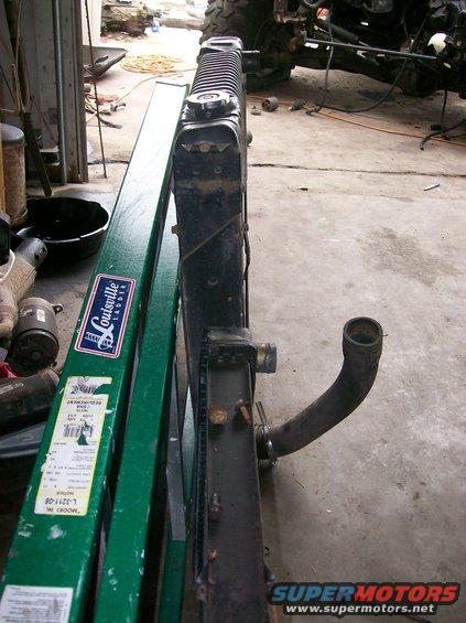Radiator with black hose attached, leaning against a green ladder