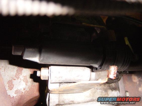 Close-up of a vehicle's exhaust pipe and mounting bracket, showing rust and a bolt