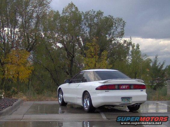 1996 Ford Probe GT rear view, white, parked on wet asphalt with trees in background