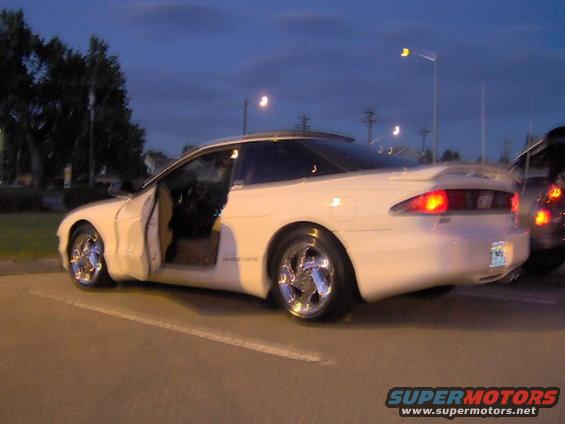 White coupe with doors open, chrome wheels, and a spoiler