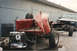 1967 Ford F-100 - Chassis of a wrecked red pickup truck with its engine and transmission exposed, parked next to another vehicle.