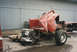 1967 Ford F-100 - The severely damaged chassis of a red pickup truck is visible, with its engine and transmission detached.