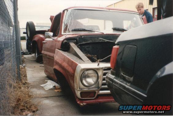 Red 1967 Ford F-100 pickup truck with hood open, parked next to a dark vehicle