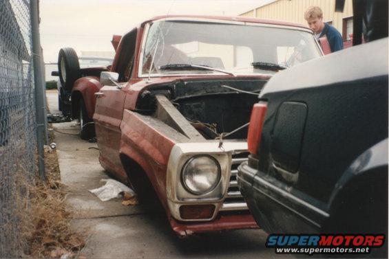 1967 Ford F-100 pickup truck, red, damaged, hood open, parked next to another vehicle