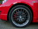 2007 Mazda 3 - The wheel and brake assembly of a red vehicle are shown in a close-up view.