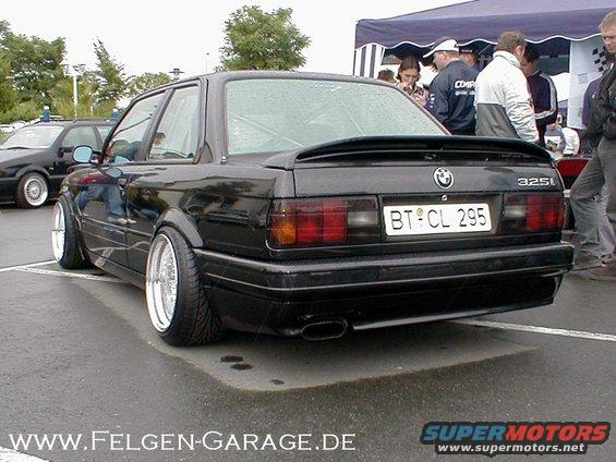Black 1989 BMW 325i rear view with custom wheels and spoiler