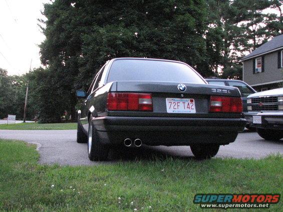 Rear view of a dark gray 1989 BMW 3 Series sedan with dual exhaust pipes and a Massachusetts license plate