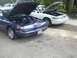 1997 Ford Crown Victoria - Two 1997 Ford Crown Victorias are parked side-by-side with their hoods open, revealing their engines.