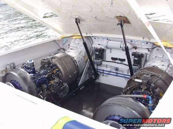 Two large jet engines installed in the engine bay of a boat, with hydraulic lifts supporting the open hatch