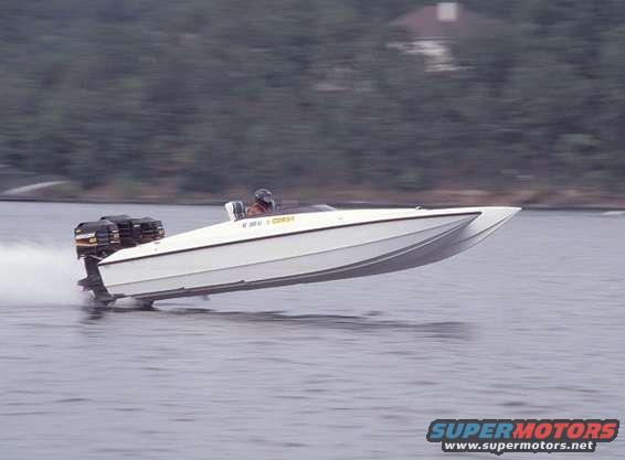 White speedboat with dual outboard motors speeding on the water. Driver is wearing a helmet