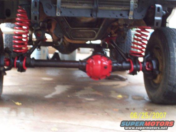 Underside view of a vehicle's front axle with red springs and differential