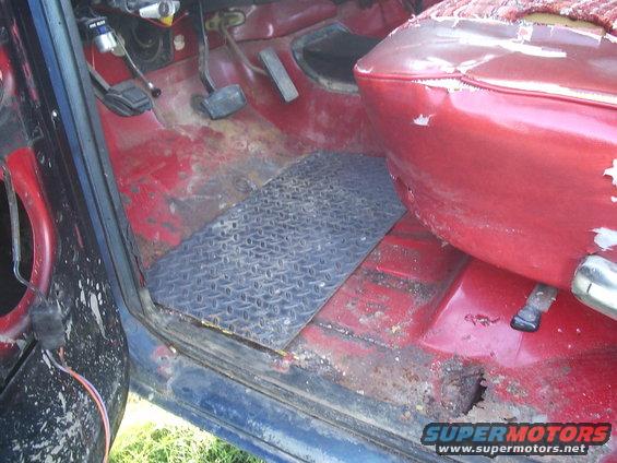 1978 Ford Bronco interior showing worn red seats, diamond plate floor mat, and rusted floor pan