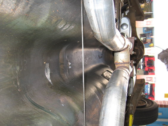 Underside view of a vehicle showing the fuel tank area and exhaust system components