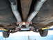 1973 Ford Ranchero - The underside of a vehicle shows a custom dual exhaust system with a driveshaft running above it.