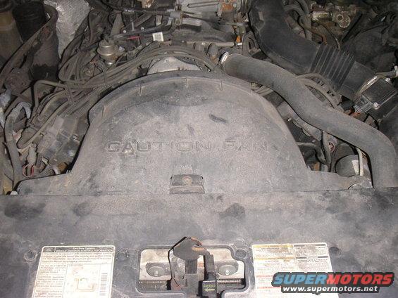 Engine bay with "CAUTION FAN" text on shroud. Labels visible