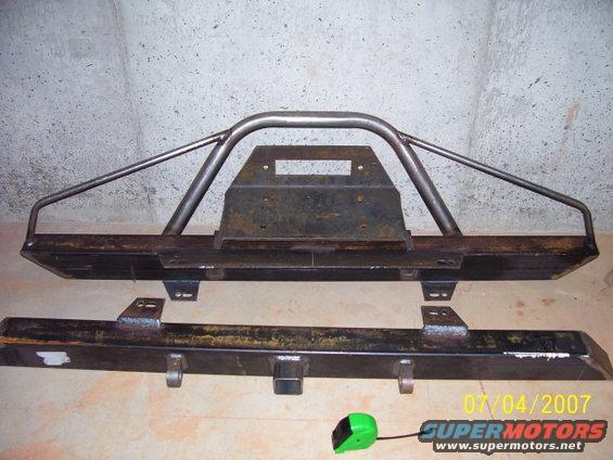 Two metal bumpers, one with a roll cage-like hoop, sit on the floor