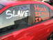 1988 Ford Bronco - A red car has messages written on its windows, including 'SLAVE' and 'Honk IF YOUR IN LOVE'.