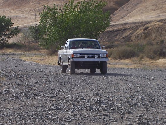White Ford F-150 pickup truck driving on a gravel road