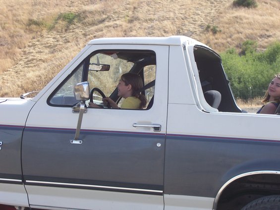 Side view of a 1991 Ford Bronco with a girl driving