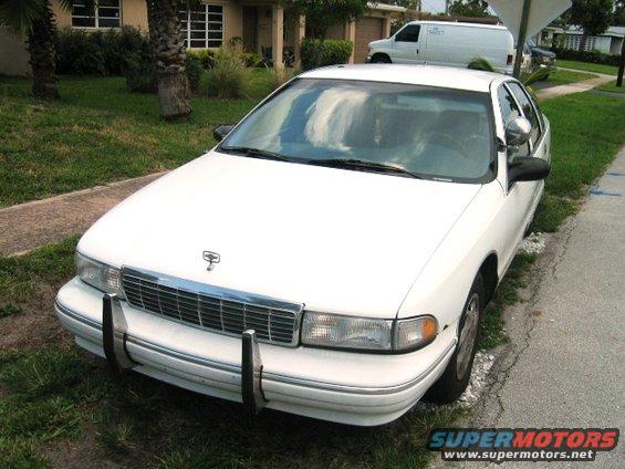 White sedan front view with chrome grille and bumpers parked on a street