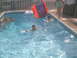 2003 Yamaha RAPTOR 80 - Children enjoy a summer day swimming and playing on an inflatable slide in a backyard pool.