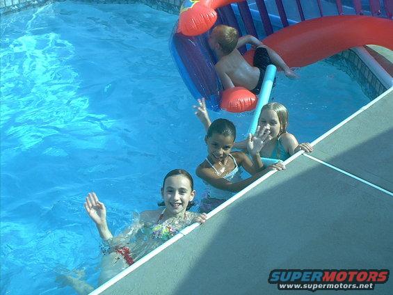 Children wave from a swimming pool with an inflatable slide