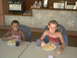 2003 Yamaha RAPTOR 80 - Two young girls are seated at tables, enjoying a meal. The girl on the right has her hair in braids.