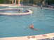 2003 Yamaha RAPTOR 80 - People enjoy a sunny day swimming in a pool with depth markers visible on the edge.