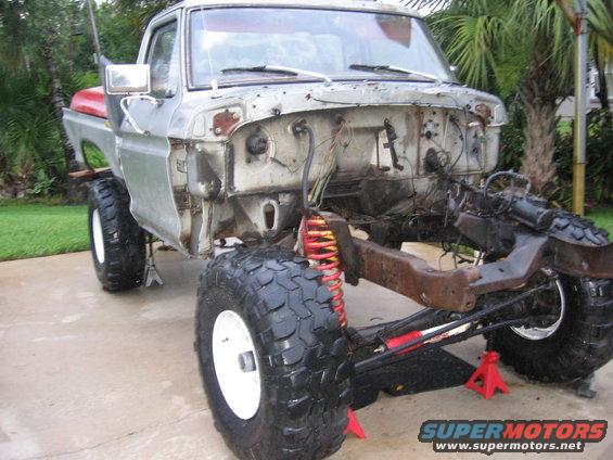 Front view of a 1973 Ford F-Series truck chassis on jack stands, with the engine and front clip removed