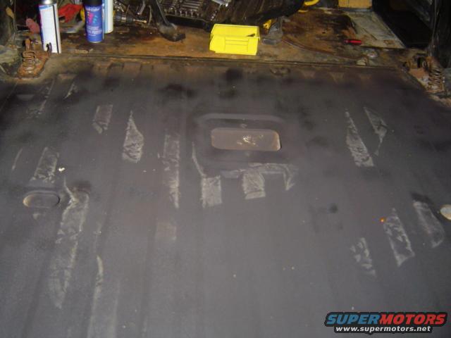 Interior floor of a vehicle, looks like it's being prepped for something. Tools and cans are on a surface behind it