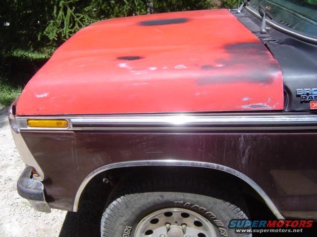Maroon and red Ford Bronco fender and hood, showing wear and tear
