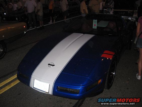 Blue Chevrolet Corvette with white racing stripes and red accents on the fender