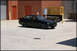 1998 BMW 3 Series - A black 1998 BMW 3 Series coupe is parked in a concrete lot with a brick building and industrial equipment in the background.