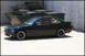 1998 BMW 3 Series - This black 1998 BMW 3 Series coupe is parked next to dumpsters and a concrete wall.