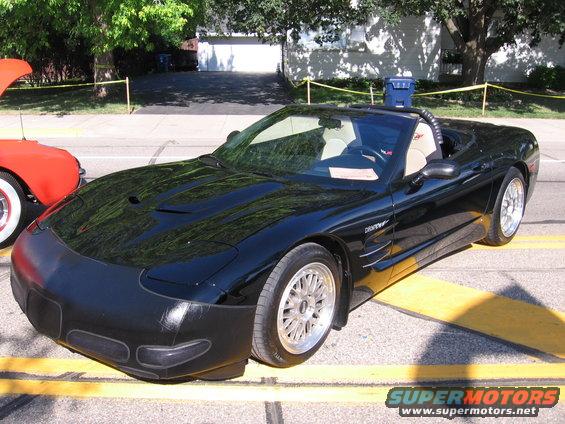 Black convertible sports car parked on street, red car with hood up next to it