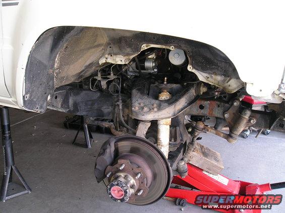 White pickup truck front suspension with disc brake and red jack