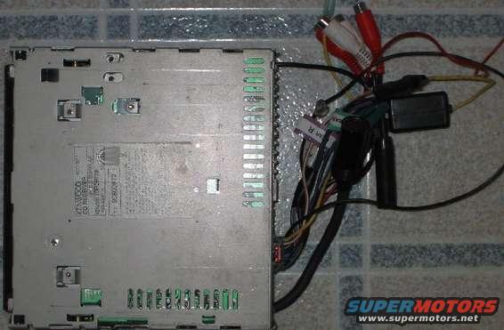 Rear view of a Kenwood CD receiver with RCA cables and wiring harness attached