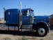 1981 Kenworth W900A - A blue Kenworth semi-truck is parked outdoors under a clear blue sky.