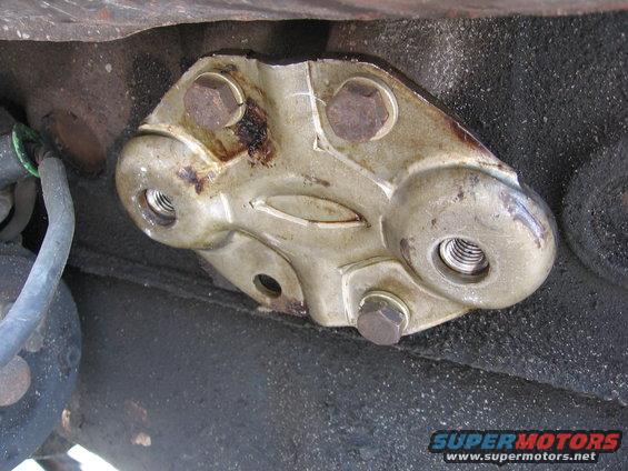 Close-up of a metal bracket bolted to a vehicle frame, with a hose nearby