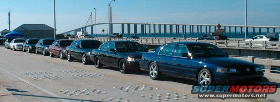Line of Ford Crown Victoria sedans, some appear to be police interceptors, parked on a bridge. 1997 Ford Crown Victoria