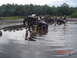 2005 Dodge 1500 - A group of people gather around an overturned ATV in a muddy, watery area. Other ATVs are visible in the background.