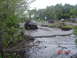 2005 Dodge 1500 - Several trucks are navigating a muddy off-road course with trees and water surrounding them.