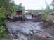 2005 Dodge 1500 - Multiple trucks navigate a challenging muddy terrain with onlookers in the background.