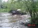 2005 Dodge 1500 - A truck is stuck in a muddy body of water, surrounded by trees and vegetation.