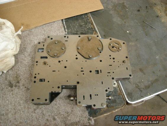 Metal plate with holes and circular components, looks like a transmission valve body